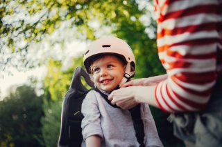 Mutter zieht ihrem Kind den Fahrradhelm an